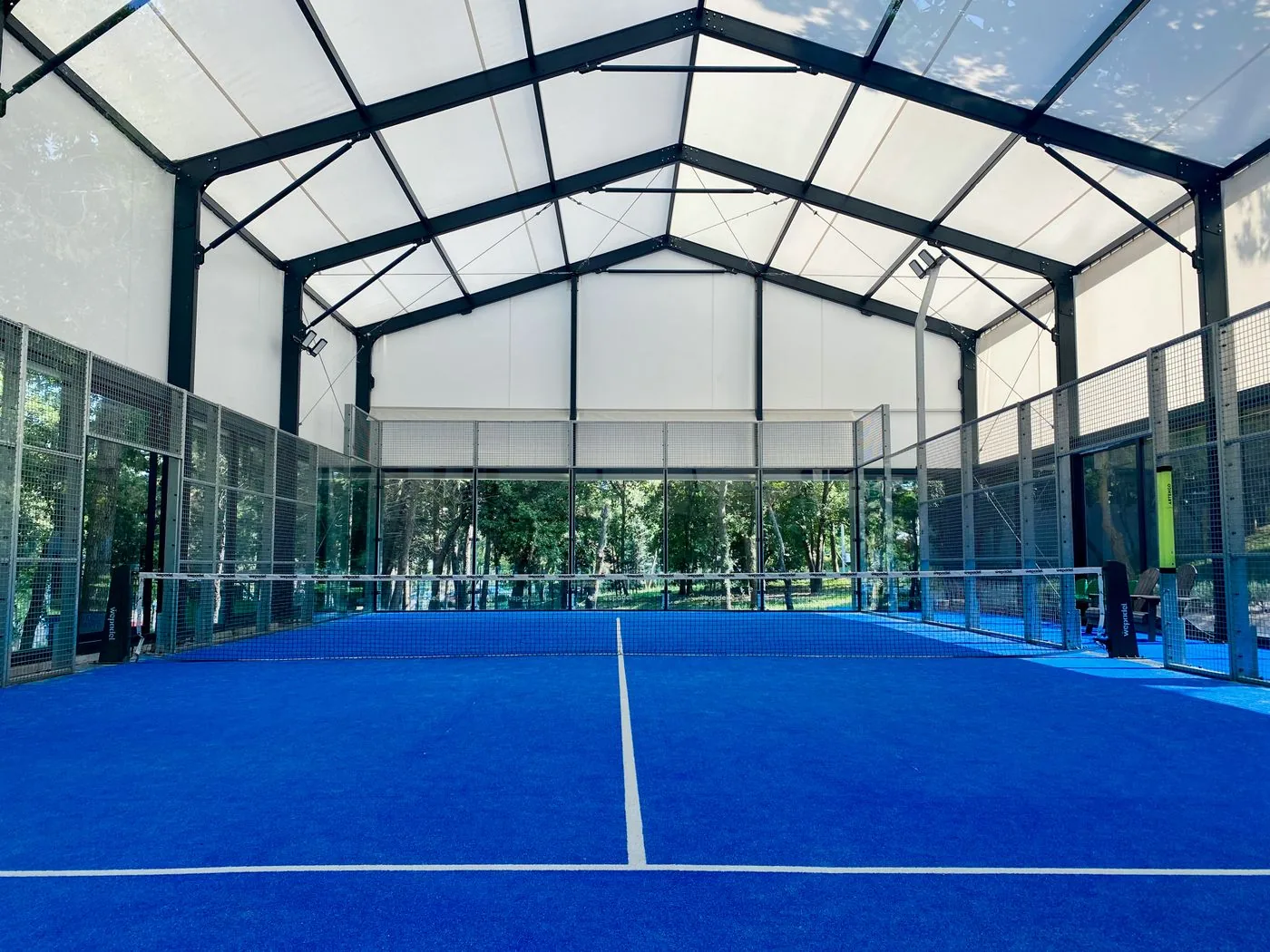 Glass-walled padel court beneath a canopy