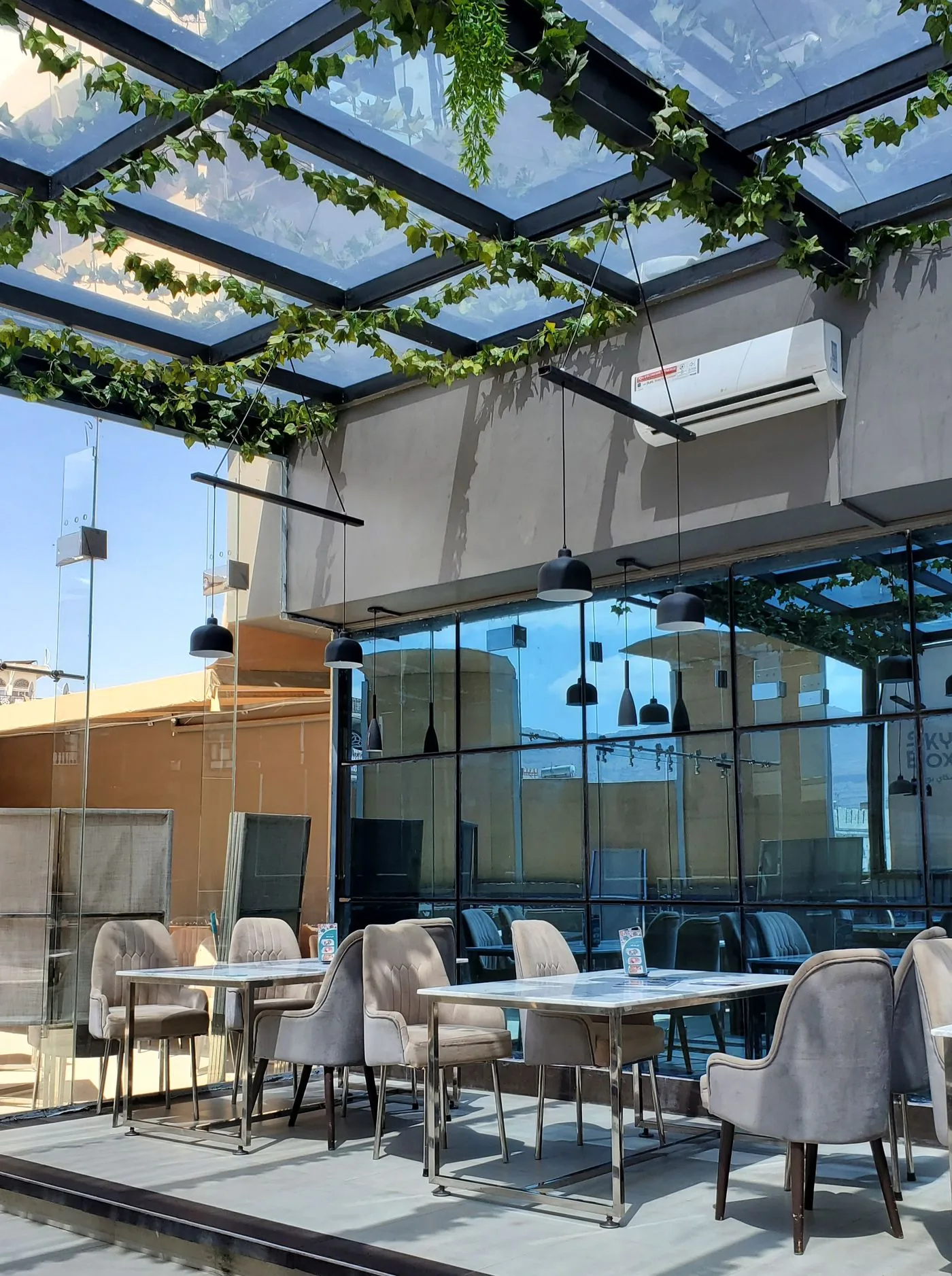 Open-air rooftop cafe beneath a greenery canopy